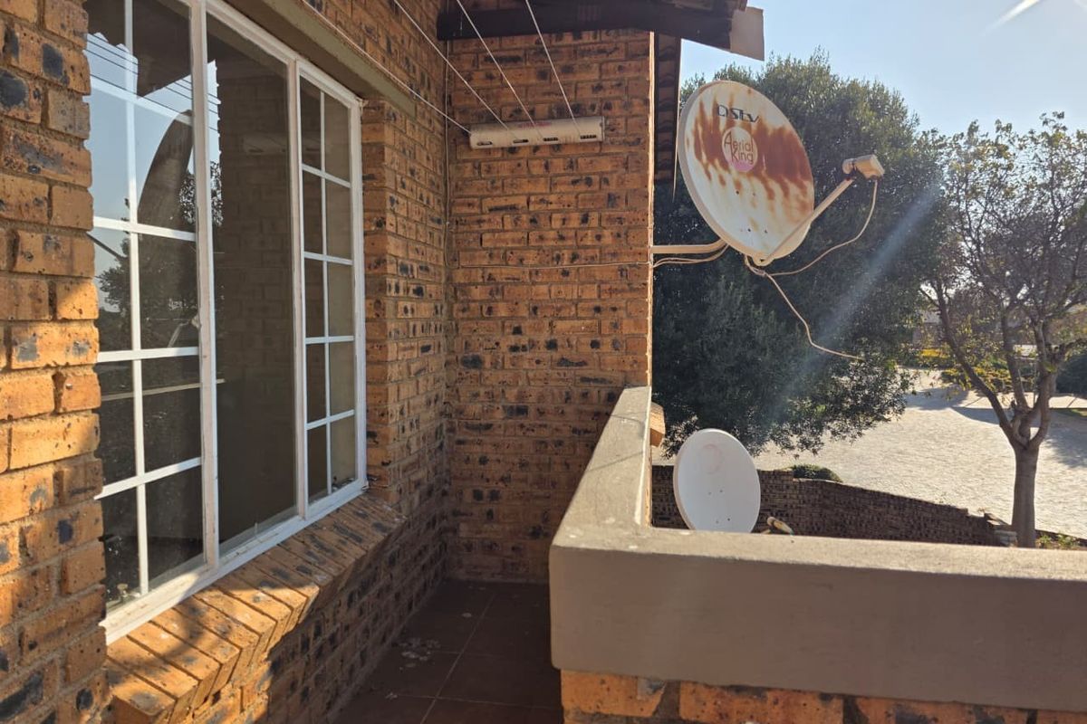 A balcony area featuring exposed brick walls, a tiled floor, and a wall-mounted washing line, with visible satellite dish infrastructure.
