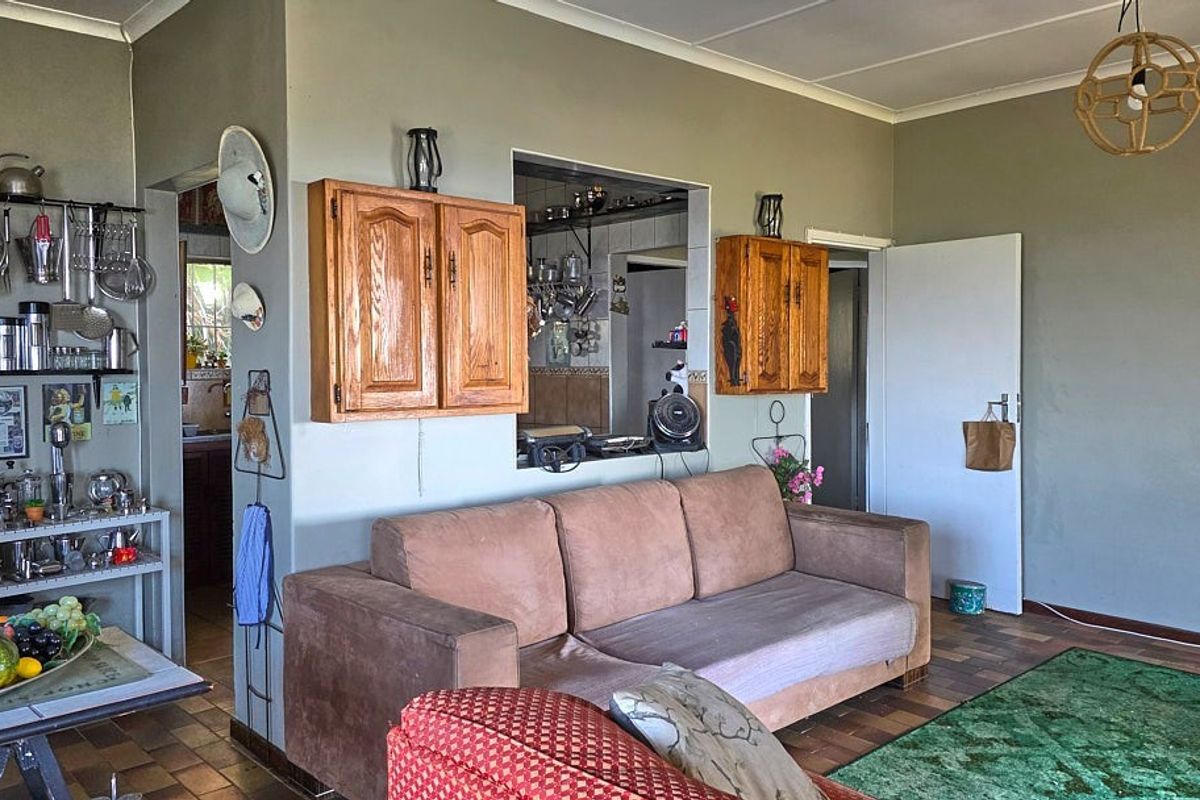 A living room featuring a serving hatch opening into the kitchen, tiled flooring, and built-in wooden wall cabinets.