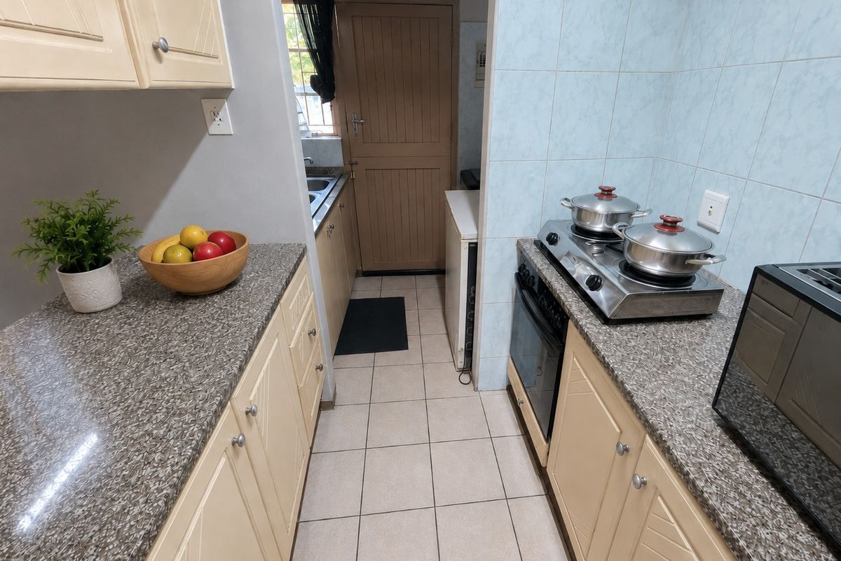 A functional kitchen featuring laminate countertops, built-in cabinetry, a gas hob, and an integrated oven, with an adjacent scullery area.