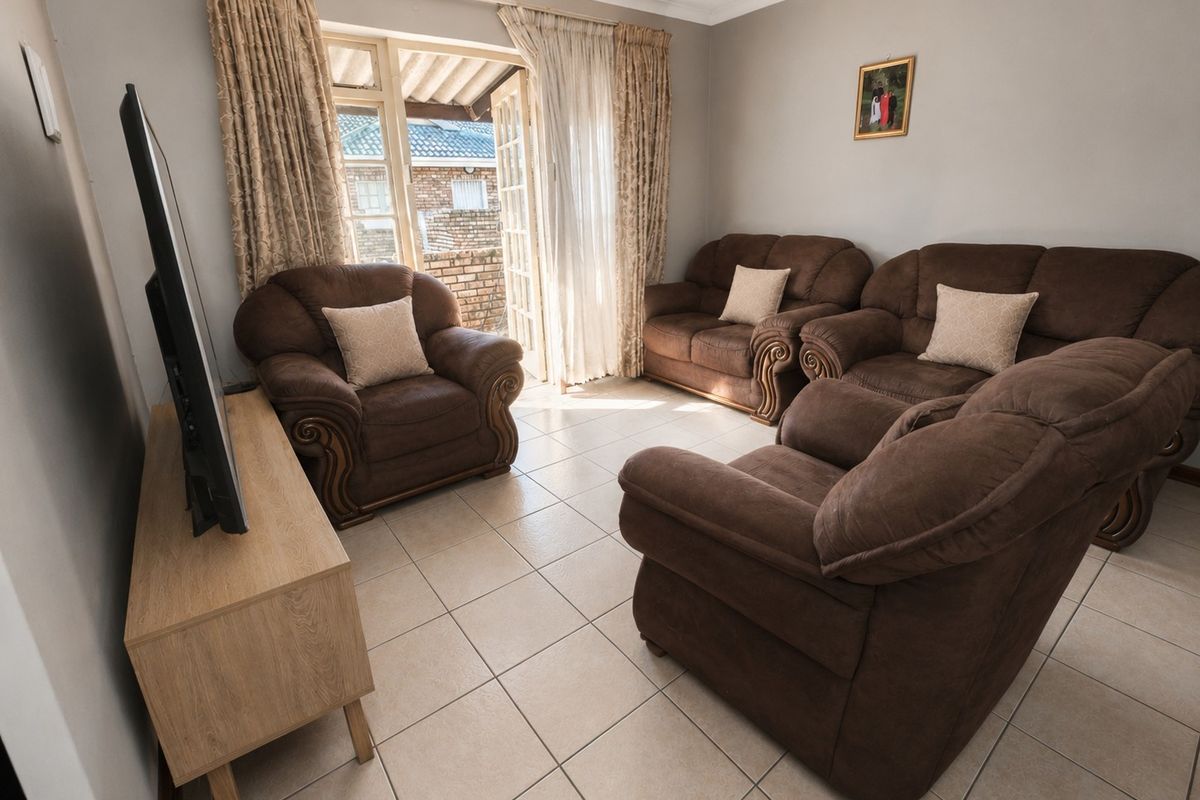 A living room featuring tiled flooring and double doors providing access to an outdoor patio area.
