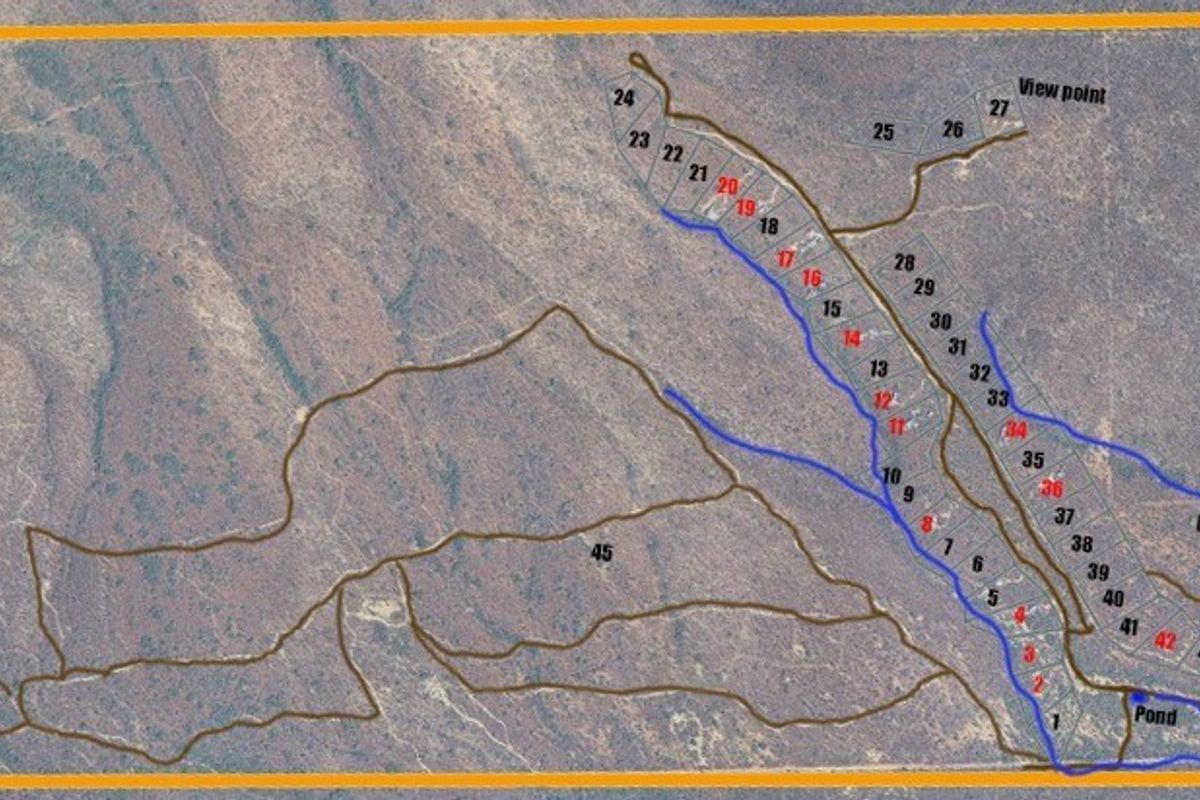 An aerial site plan showing the layout of residential plots, access roads, a dam, and a farmhouse on the property.