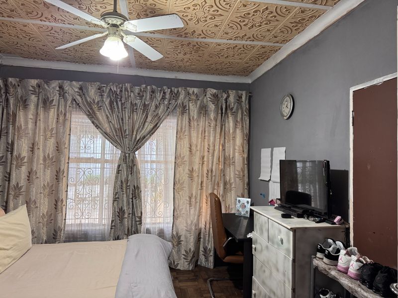 Bedroom featuring a unique decorative pressed metal ceiling, parquet flooring, and security bars on the windows.