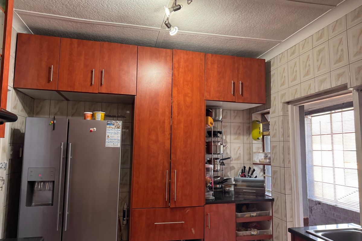 A functional kitchen featuring wood-look cabinetry, tiled backsplash, and integrated storage space, offering a practical layout for daily meal preparation.