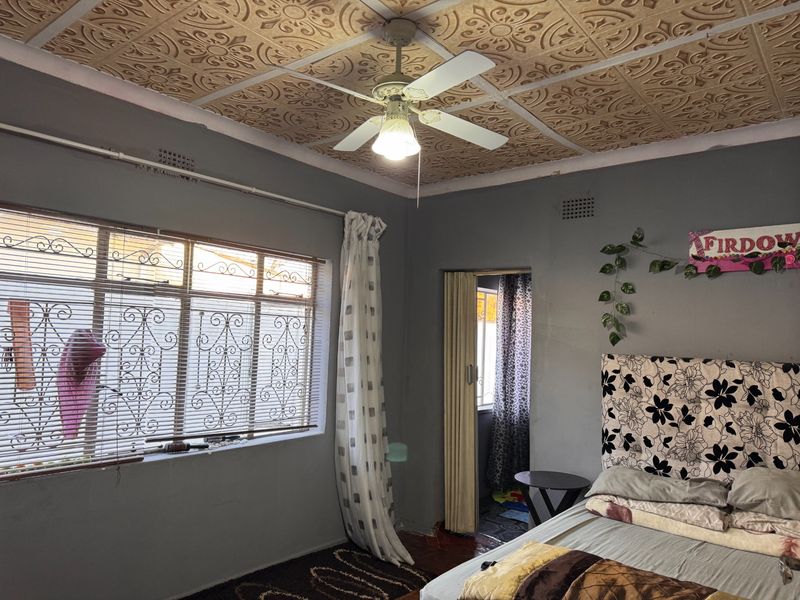 Bedroom featuring a unique decorative ceiling, ceiling fan, and metal security window bars. The space offers potential for cosmetic updates to enhance its appeal.