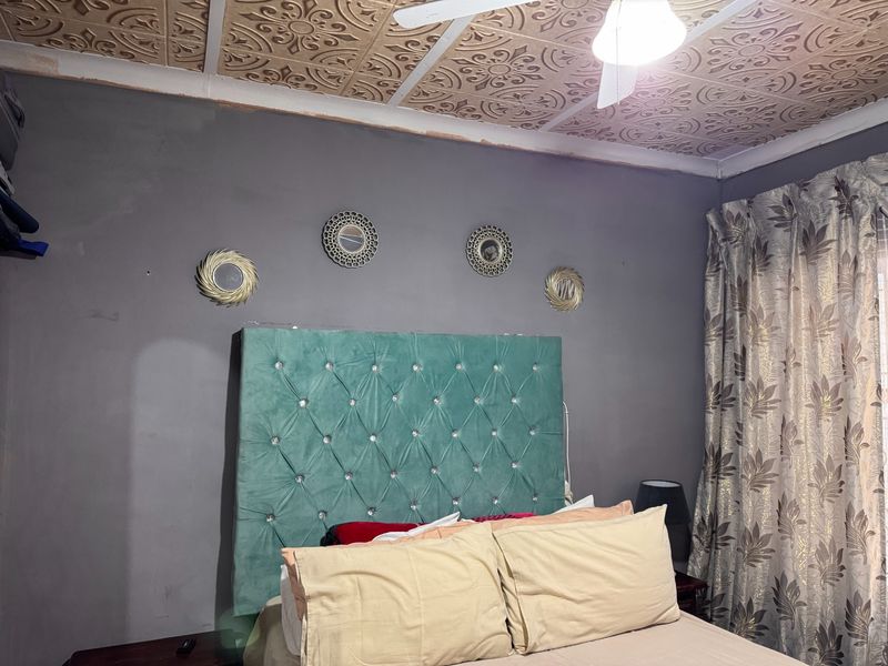 Bedroom featuring a unique decorative pressed metal ceiling and ceiling fan, requiring minor cosmetic updates to wall finishes.