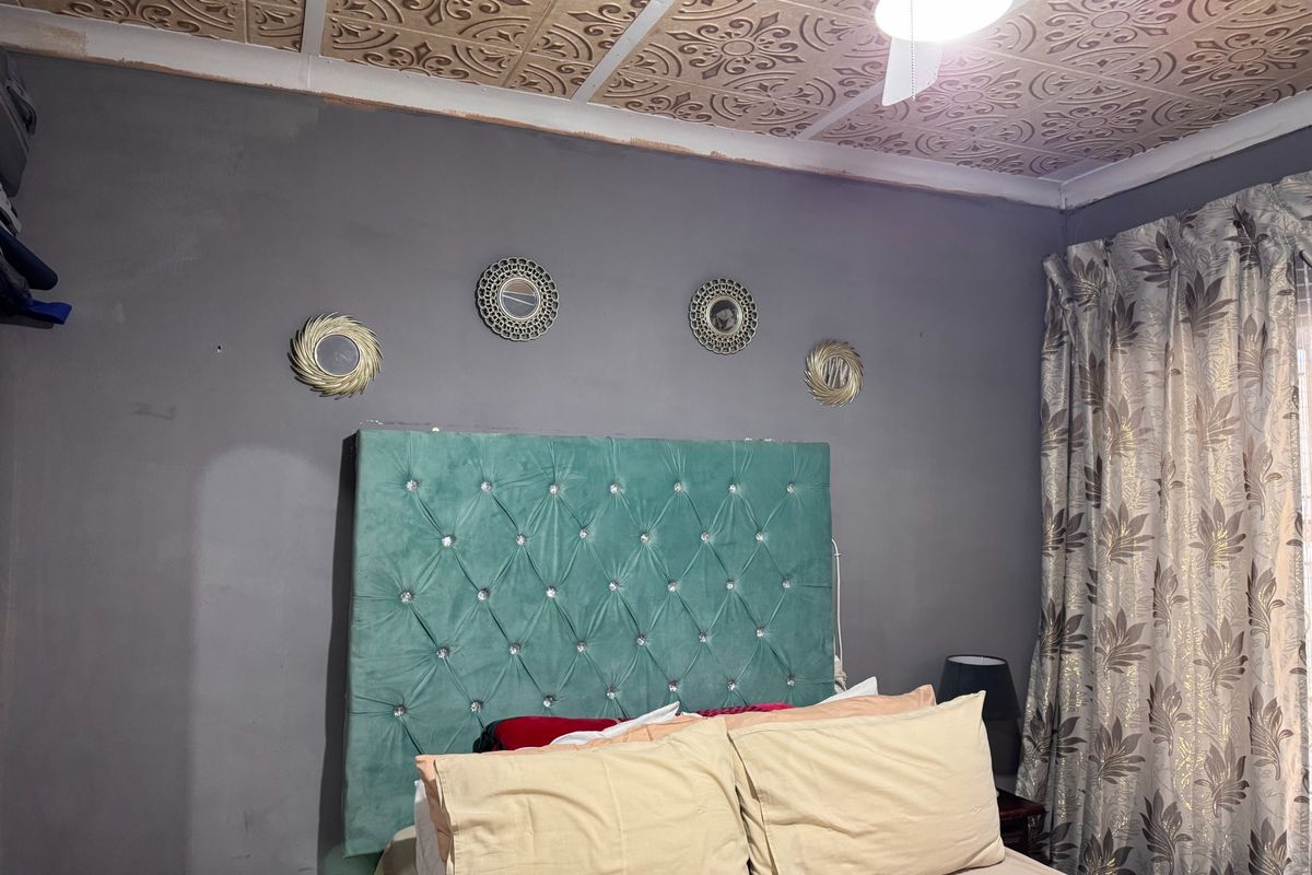 Bedroom featuring a unique decorative pressed metal ceiling and ceiling fan, requiring minor cosmetic updates to wall finishes.