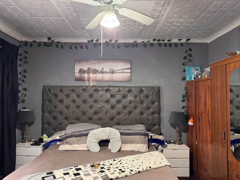 A bedroom featuring a ceiling fan and decorative textured ceiling tiles.