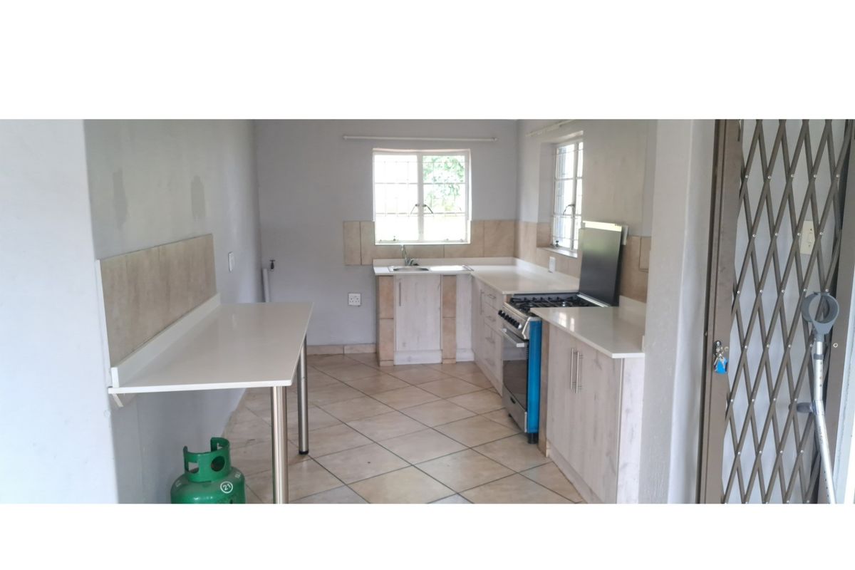 A functional kitchen featuring built-in cabinetry, stone countertops, a gas stove, and tiled flooring, offering a clean space ready for personalization.