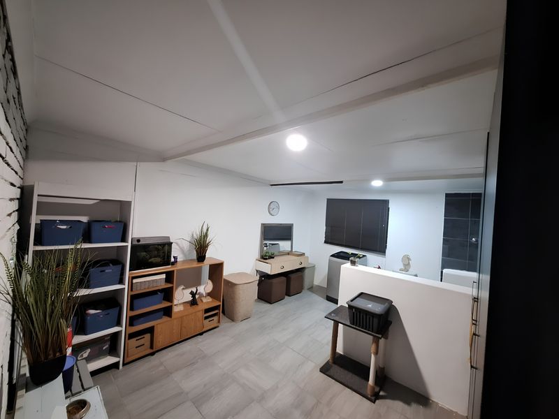 An open-plan living space featuring tiled flooring, a partial room divider, and recessed ceiling lighting, offering a versatile layout for various living arrangements.