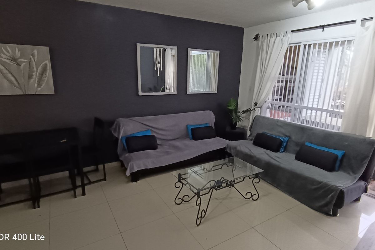 A living room featuring large format floor tiles, a dark accent wall, and sliding glass doors providing access to an outdoor patio area.