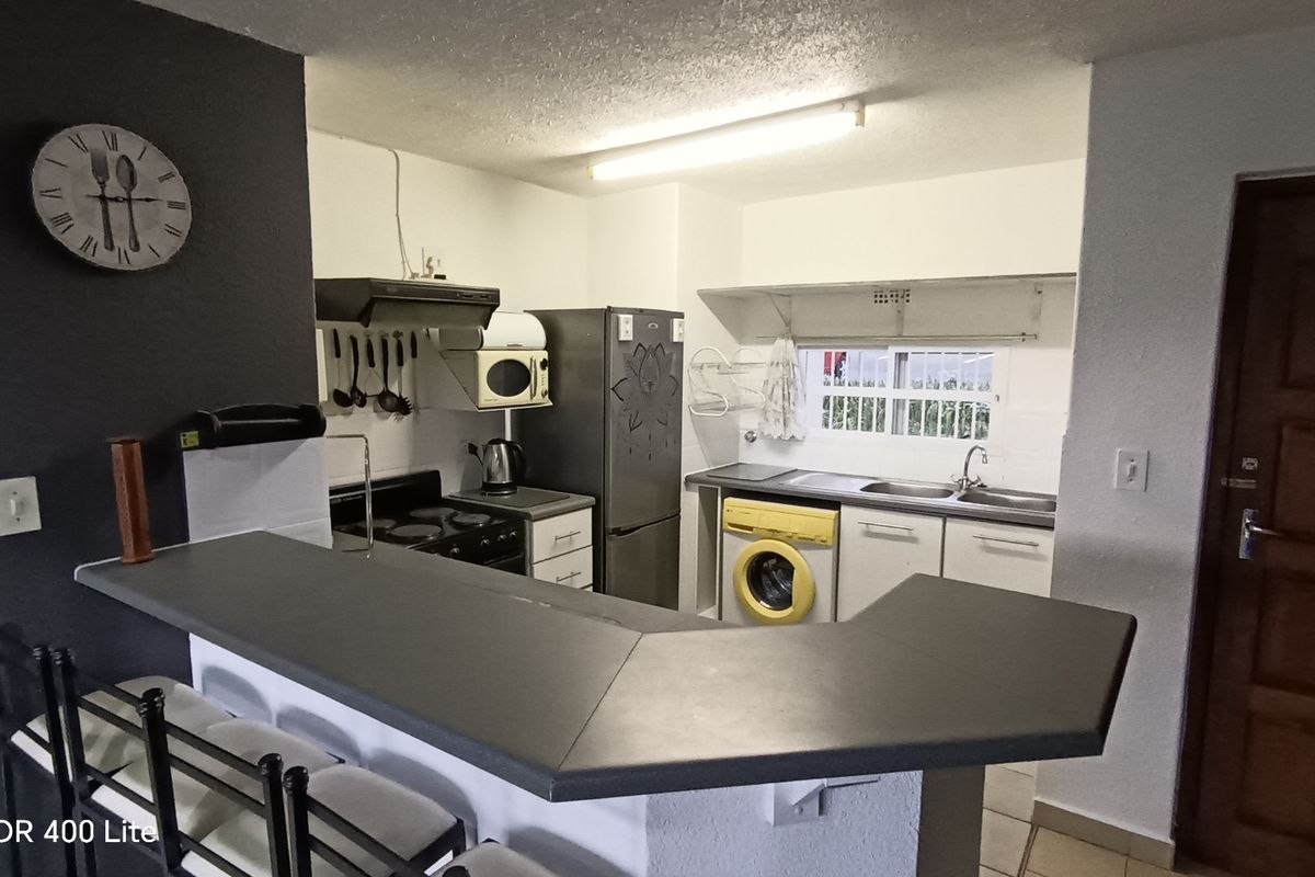 Functional kitchen featuring a breakfast bar, built-in cabinetry, stainless steel sink, and integrated stove with extractor fan.