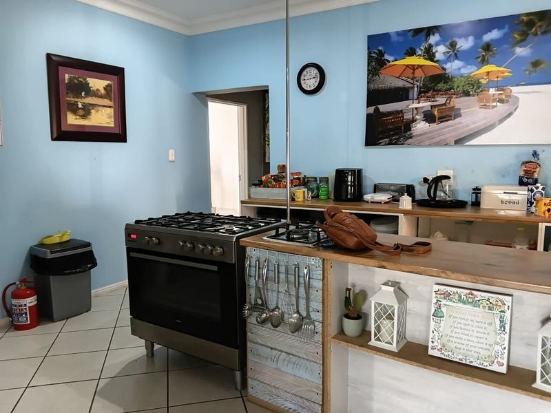 A functional kitchen area featuring a freestanding gas stove, tiled flooring, and built-in cabinetry with a breakfast bar counter.