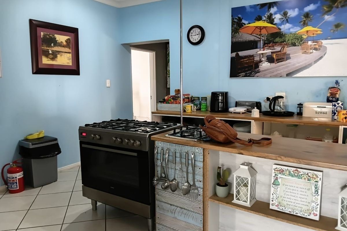 A functional kitchen area featuring a freestanding gas stove, tiled flooring, and built-in cabinetry with a breakfast bar counter.