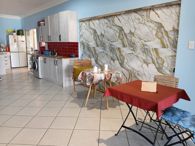 Kitchen area featuring built-in cabinetry, tiled splashback, and a decorative marble-effect feature wall with tiled flooring throughout.