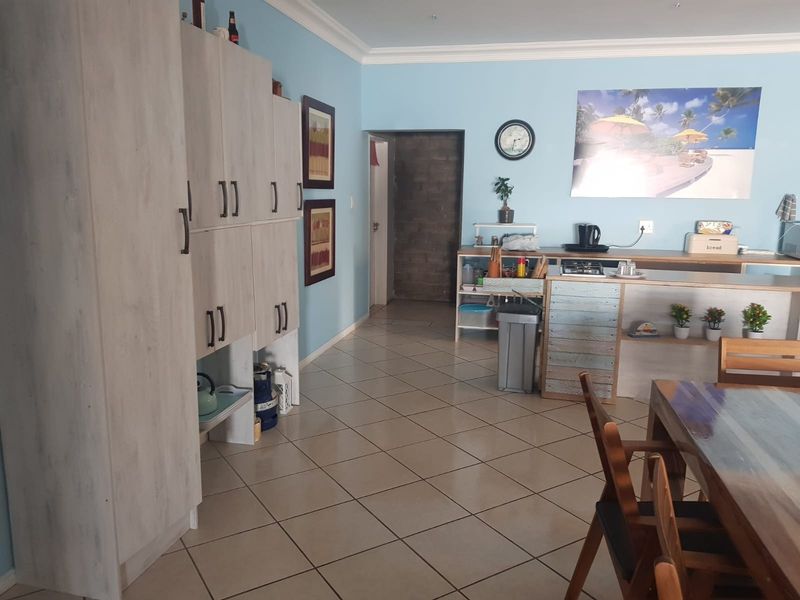 Open plan living and kitchen area featuring tiled flooring, built-in cabinetry, and a breakfast counter, providing a functional and connected living space.