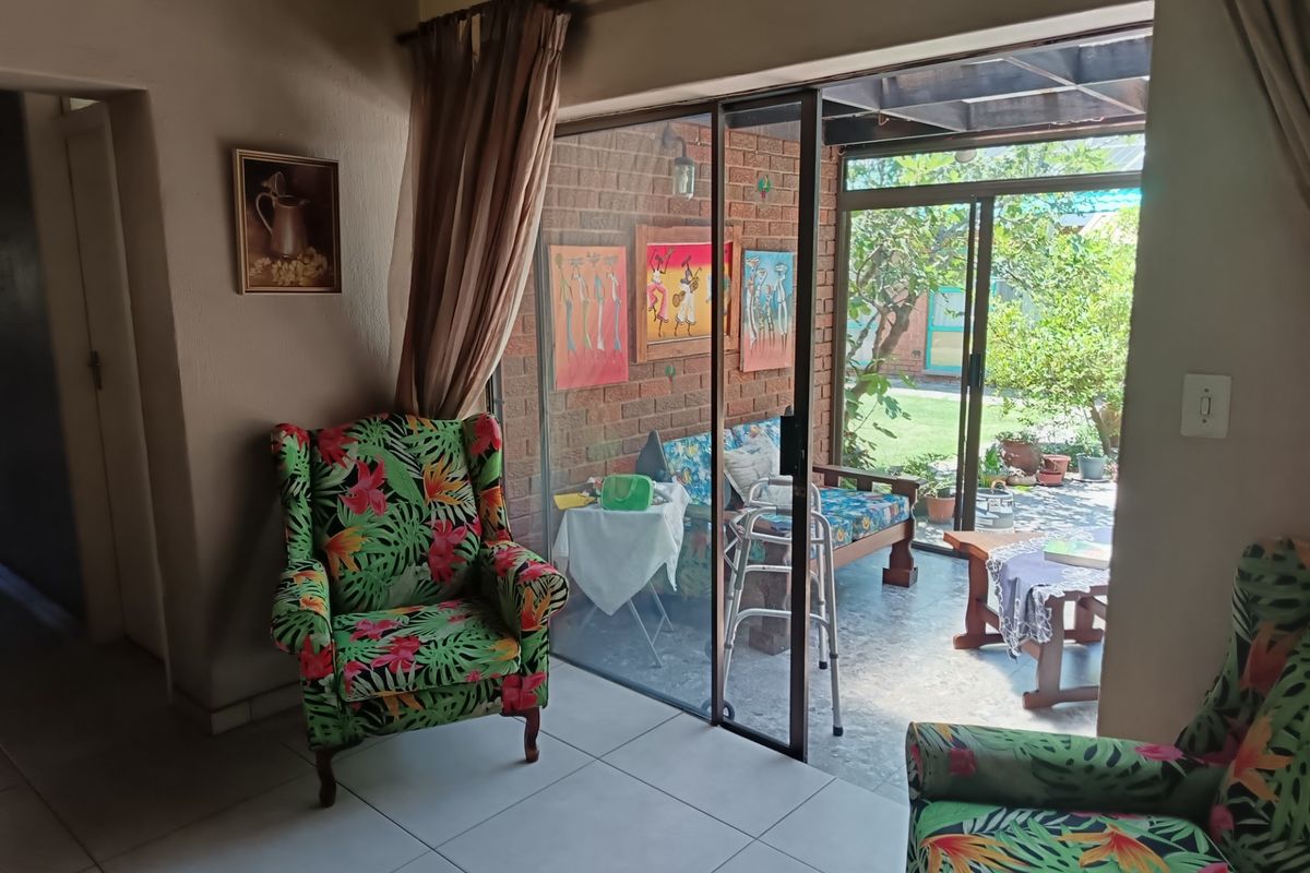 Living room featuring tiled flooring and a large sliding glass door providing direct access to a covered patio and garden area.