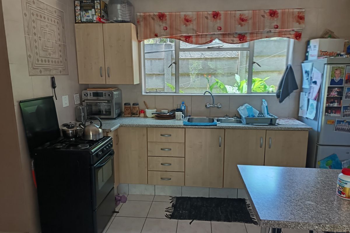 A functional kitchen featuring laminate cabinetry, tiled flooring, and a double bowl sink with a window overlooking the rear exterior.