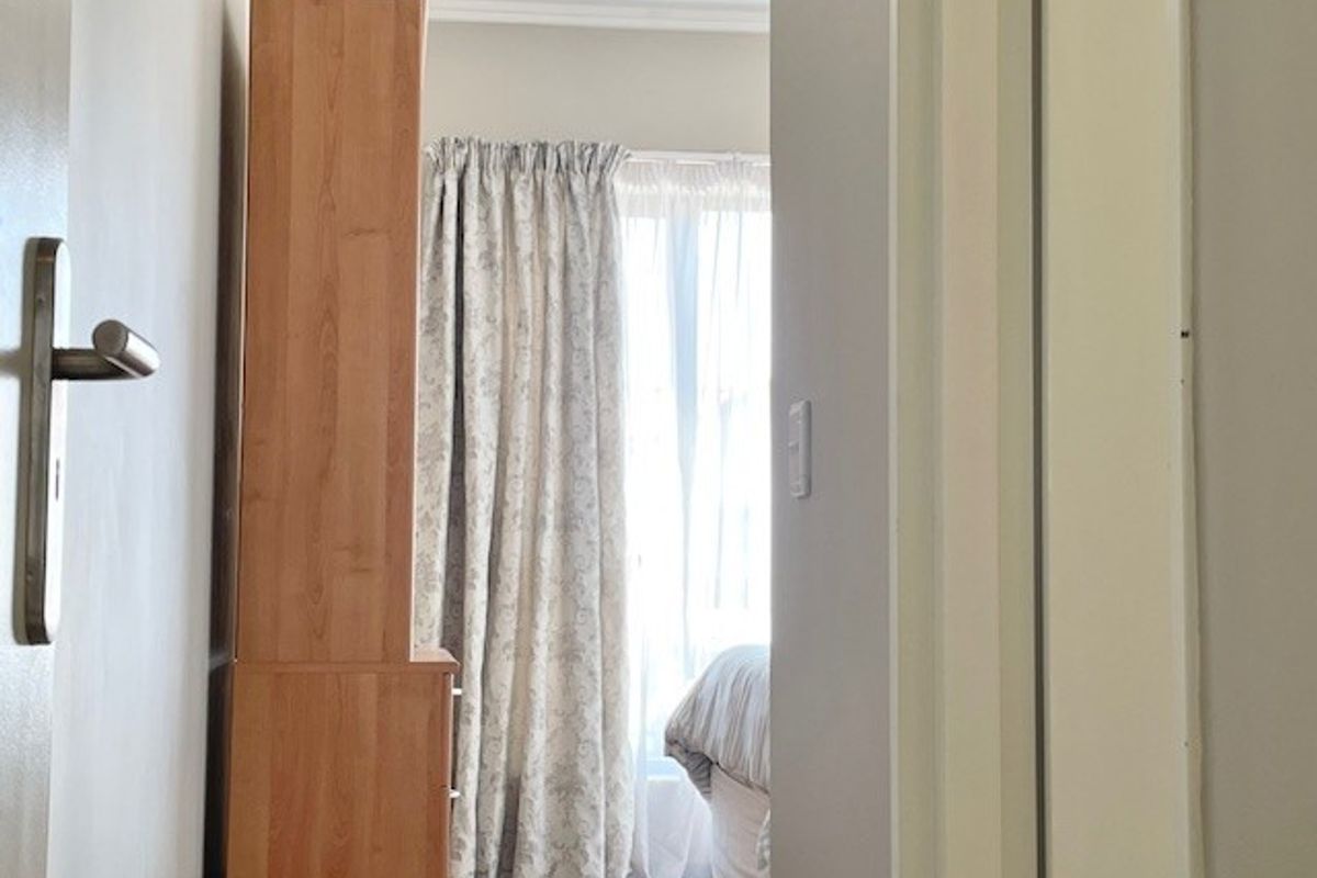 A view through a doorway into a bedroom featuring a window with curtains and neutral wall finishes.