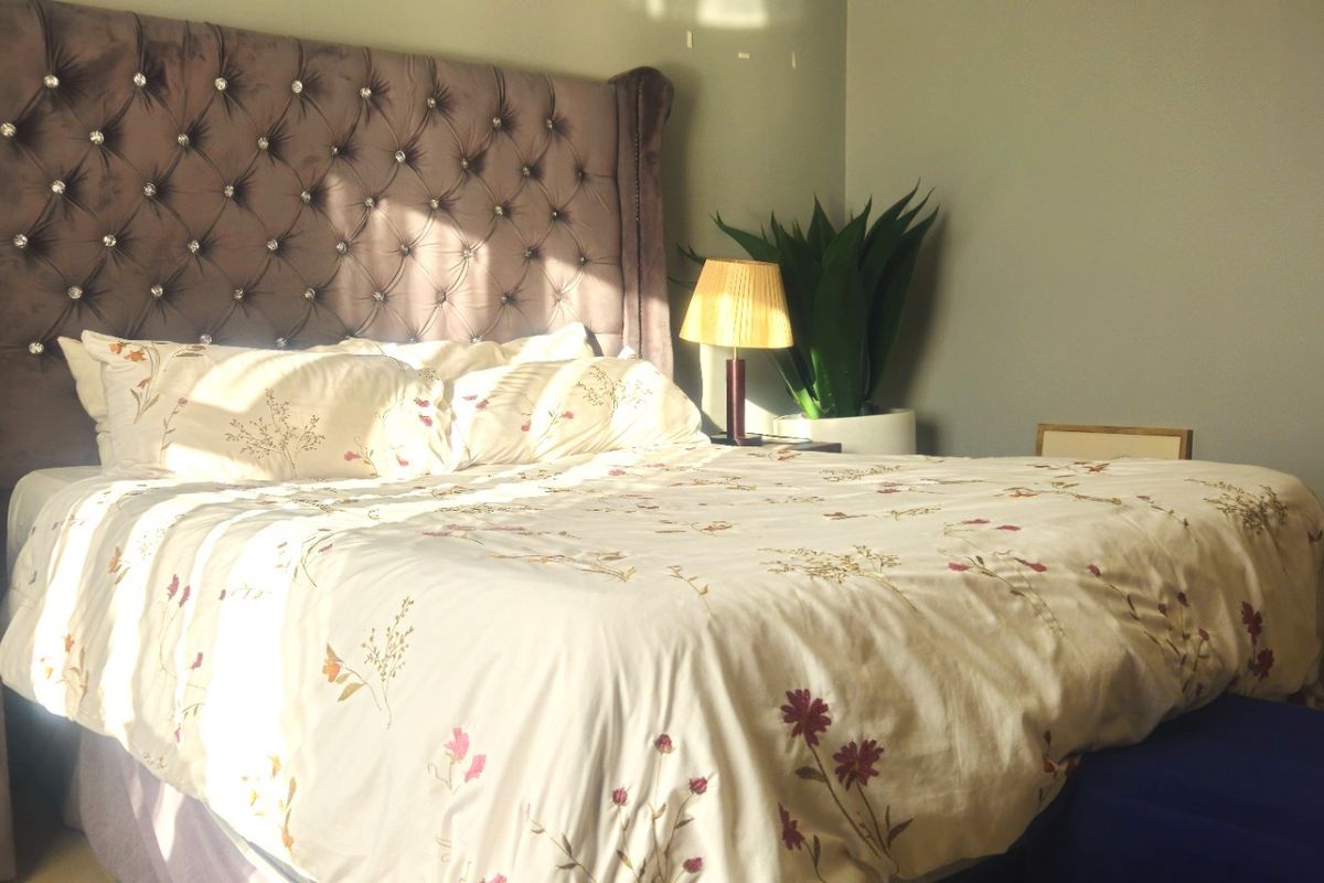 A well-lit bedroom featuring a tufted upholstered headboard and neutral wall finishes.