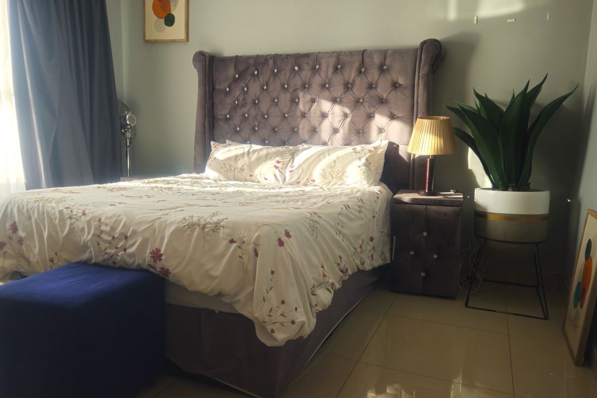 A well-lit bedroom featuring neutral wall tones and polished tiled flooring, providing a comfortable and functional sleeping space.
