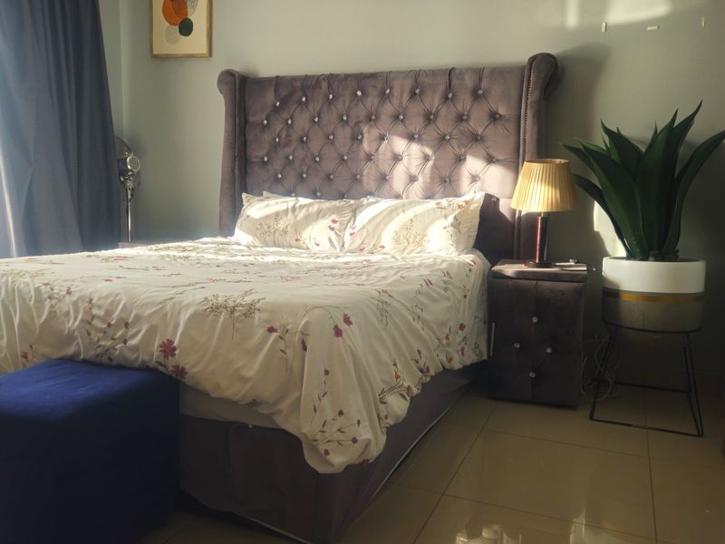 A well-lit bedroom featuring neutral wall tones and polished tiled flooring, providing a comfortable and functional sleeping space.