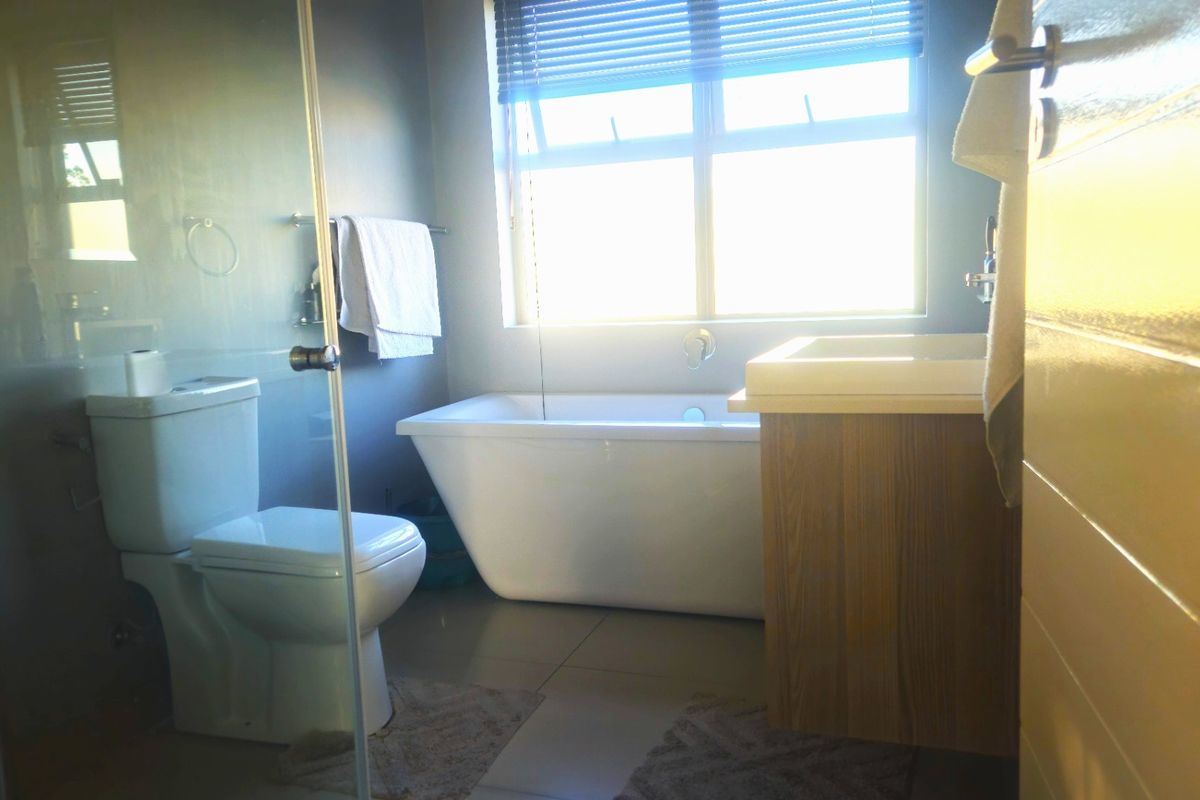 Modern bathroom featuring a freestanding bathtub, glass-enclosed shower, and a wooden vanity cabinet with a basin.