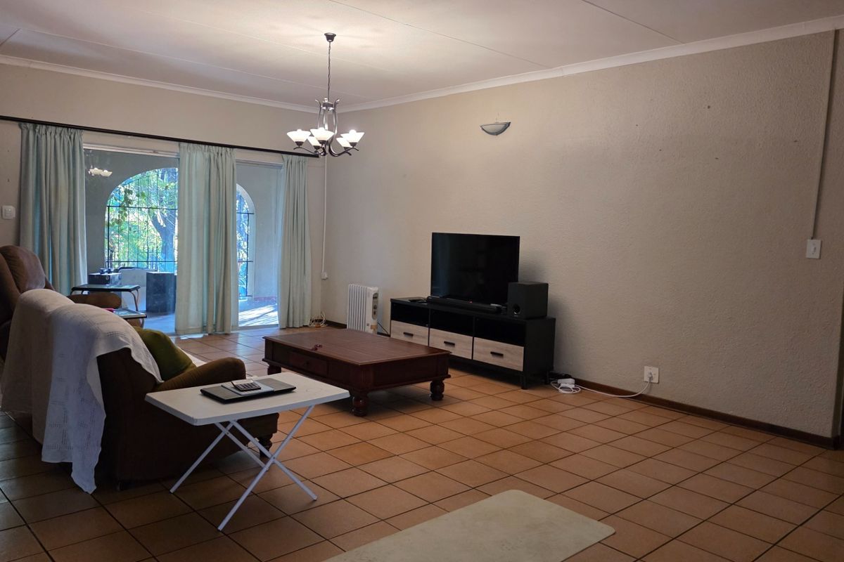 Spacious living room featuring neutral walls, tiled flooring, and large sliding glass doors providing access to the outdoor patio area.