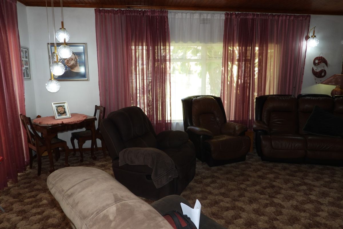 A living room featuring a timber tongue and groove ceiling and carpeted flooring, offering a traditional aesthetic with potential for modern updates.