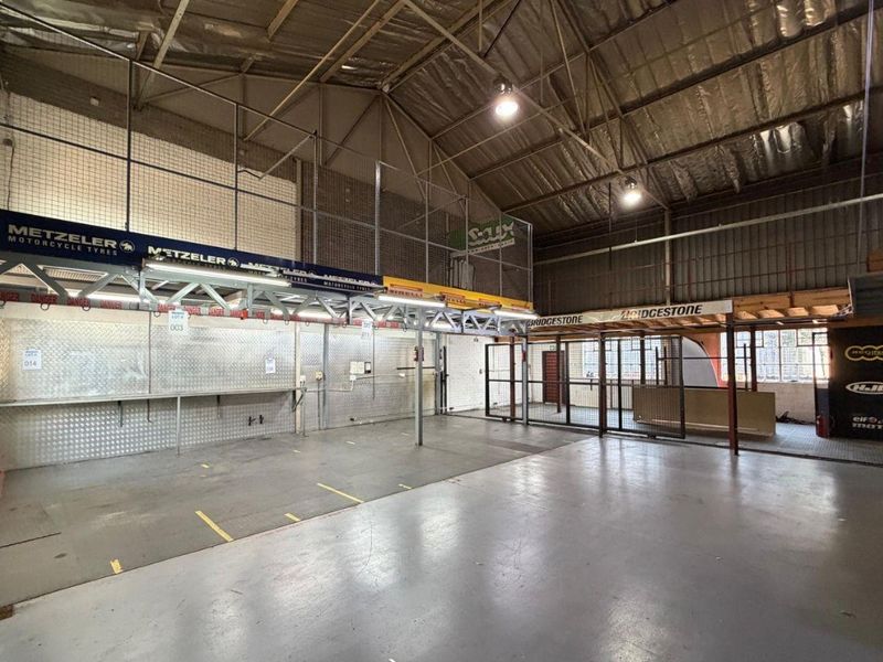 Spacious industrial utility area featuring high ceilings with exposed steel trusses, a mezzanine level, metal wall cladding, and durable concrete flooring.