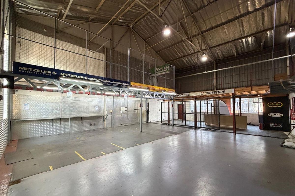 Spacious industrial utility area featuring high ceilings with exposed steel trusses, a mezzanine level, metal wall cladding, and durable concrete flooring.