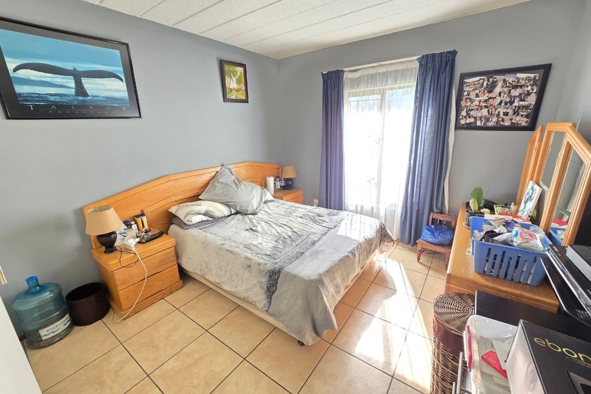 A bedroom featuring tiled flooring, a built-in wooden headboard, and a sliding glass door providing natural light.