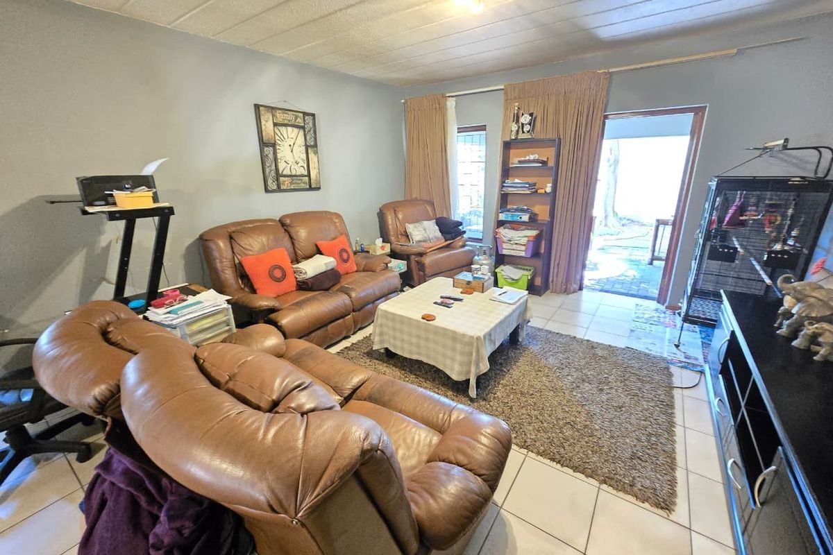 A living room featuring tiled flooring and direct access to an outdoor patio area through a glass door.