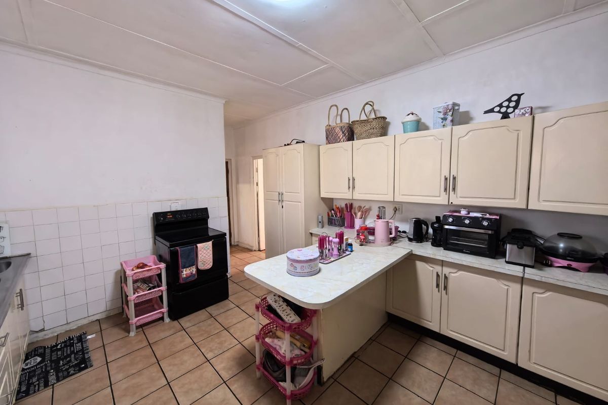 A functional kitchen featuring tiled flooring, laminate countertops, and built-in cabinetry, offering a practical layout with potential for modern updates.