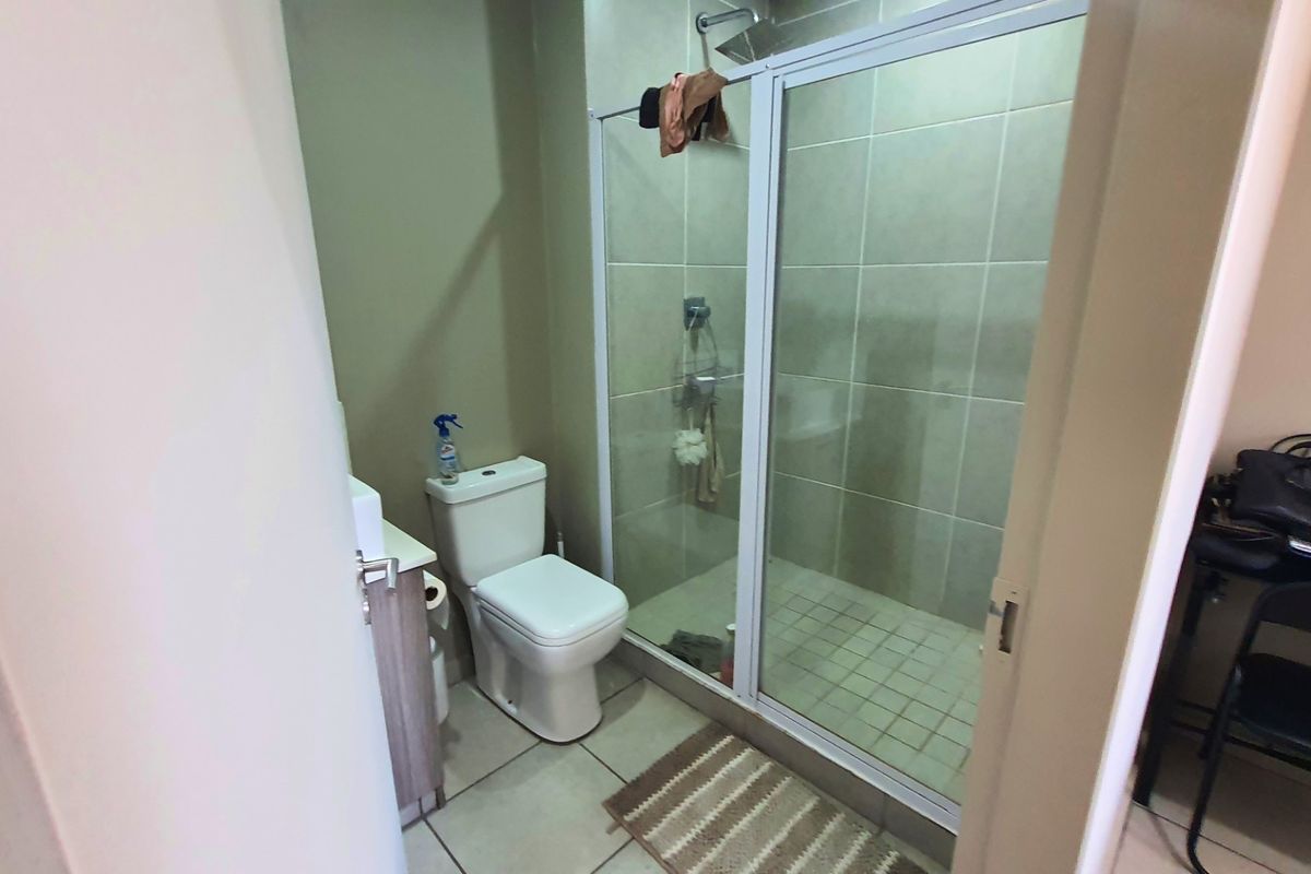 A functional bathroom featuring a glass-enclosed shower, a standard toilet, and a vanity unit with a basin.