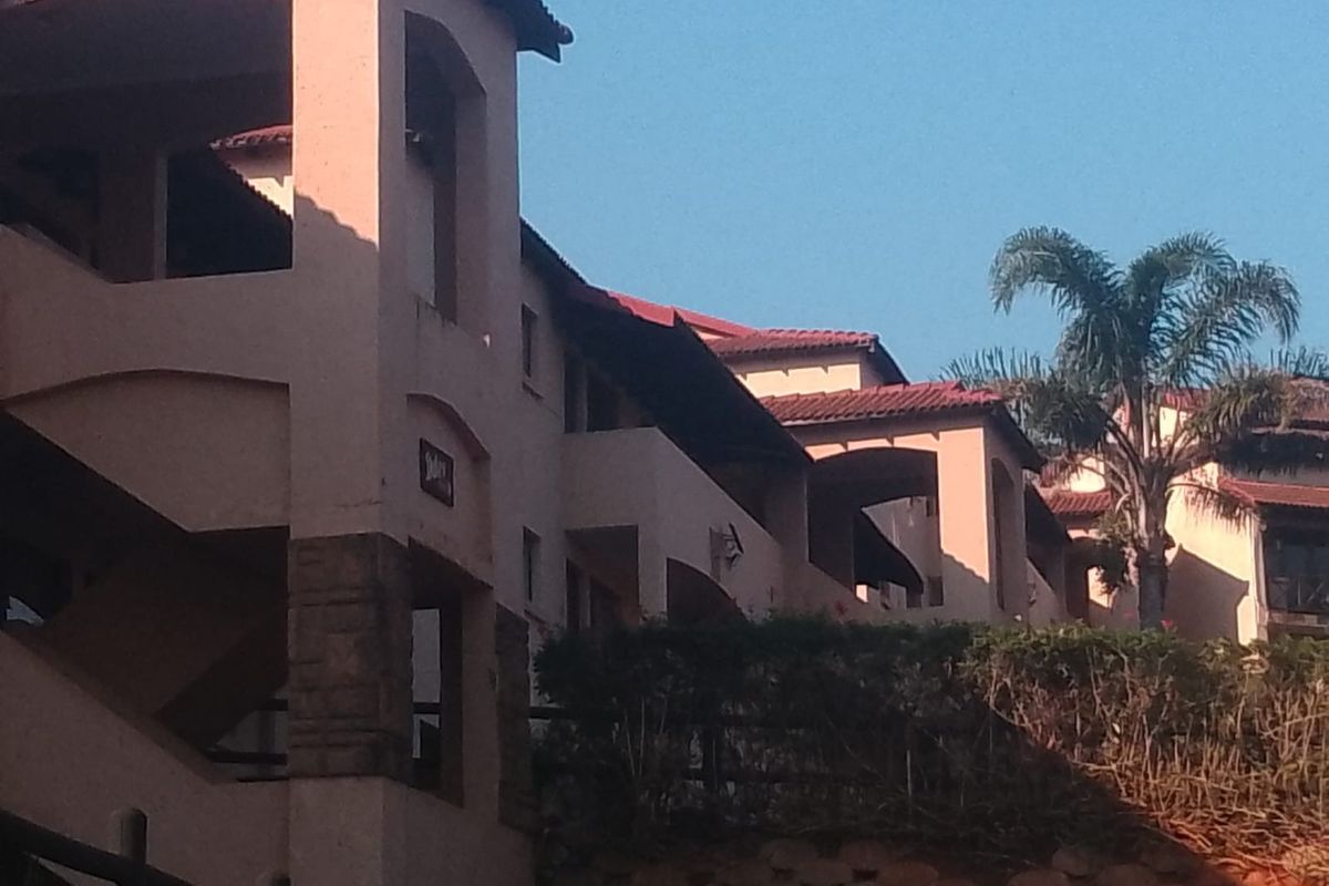 Exterior view of a multi-story apartment complex featuring stucco facades, tiled roofs, and integrated balcony spaces.