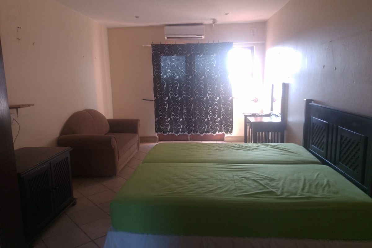 A bedroom featuring tiled flooring, a wall-mounted air conditioning unit, and access to an outdoor area through a glass door.