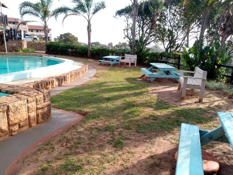 Communal outdoor pool area featuring a swimming pool with stone retaining walls and surrounding garden space.