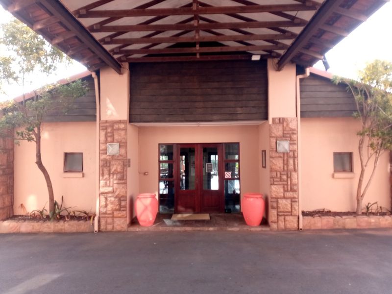 The front entrance features a covered porte-cochere with timber roof trusses, stone-clad pillars, and double timber doors.