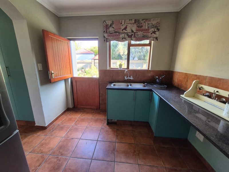 A functional scullery area featuring tiled flooring, granite countertops, a double sink, and a stable door providing direct access to the exterior.