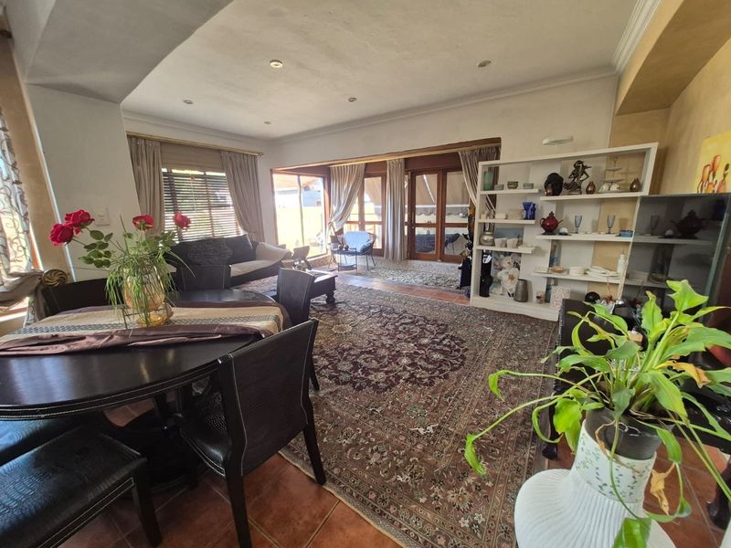 Spacious open-plan living and dining area featuring terracotta floor tiles, recessed lighting, and large sliding glass doors providing access to the outdoor space.