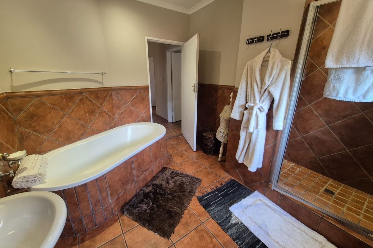 A functional bathroom featuring a built-in bathtub, separate shower enclosure, and warm-toned ceramic wall and floor tiling.