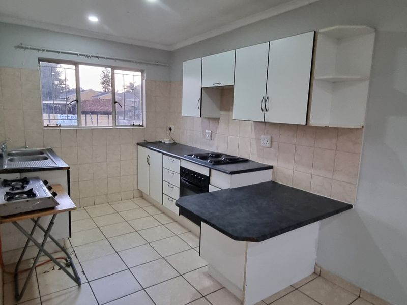 A functional kitchen featuring built-in cabinetry, laminate countertops, a built-in oven with hob, and tiled splashbacks. The space is clean and ready for updates.