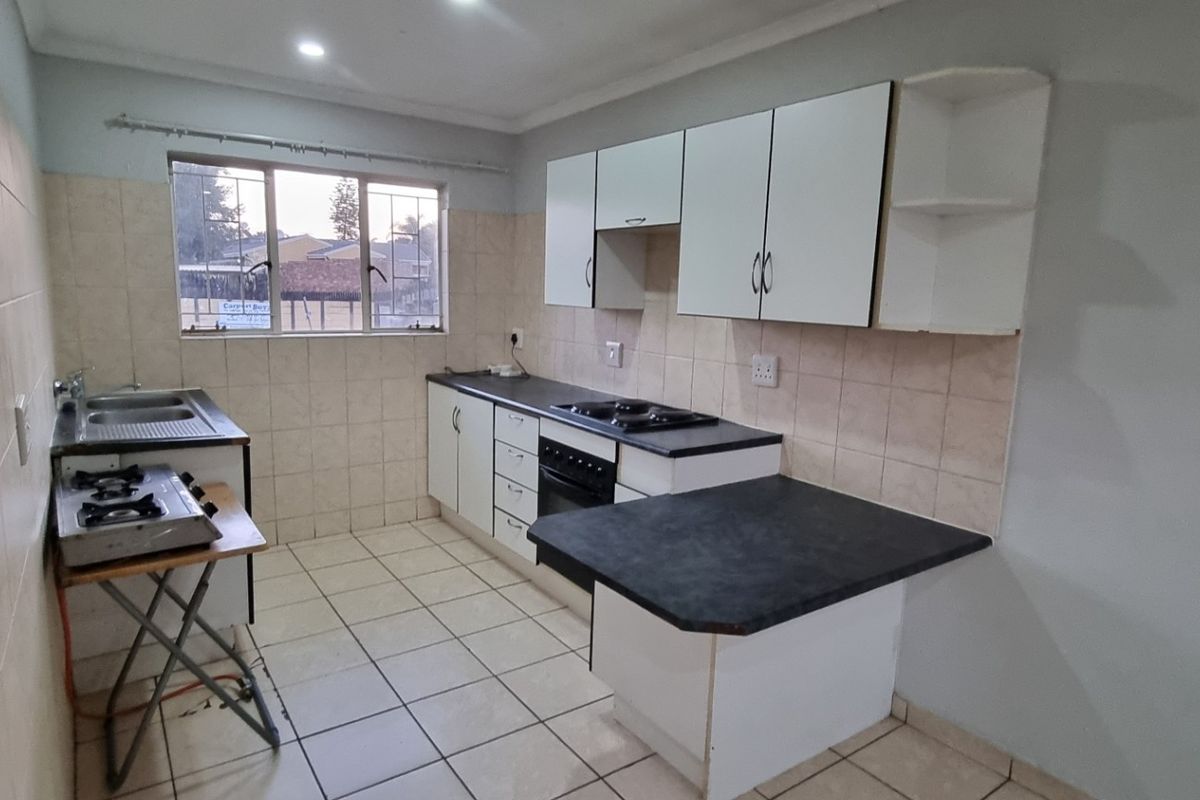 A functional kitchen featuring built-in cabinetry, laminate countertops, a built-in oven with hob, and tiled splashbacks. The space is clean and ready for updates.