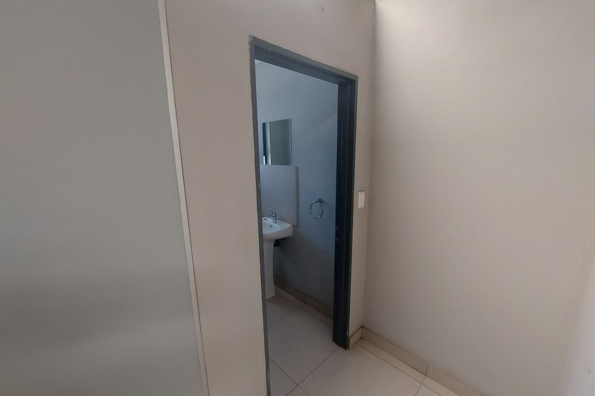 A view through a doorway into a small bathroom featuring a pedestal basin and tiled flooring.