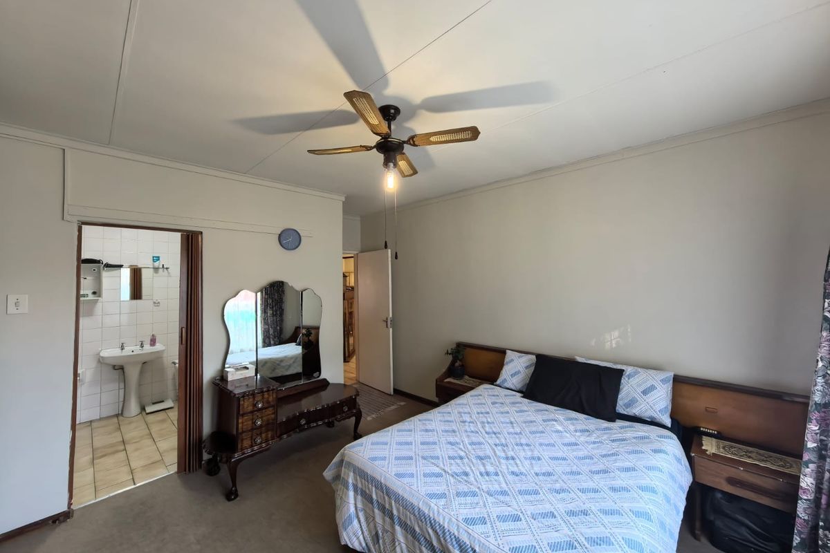 A bedroom featuring a ceiling fan and an en-suite bathroom with a pedestal basin and tiled flooring.