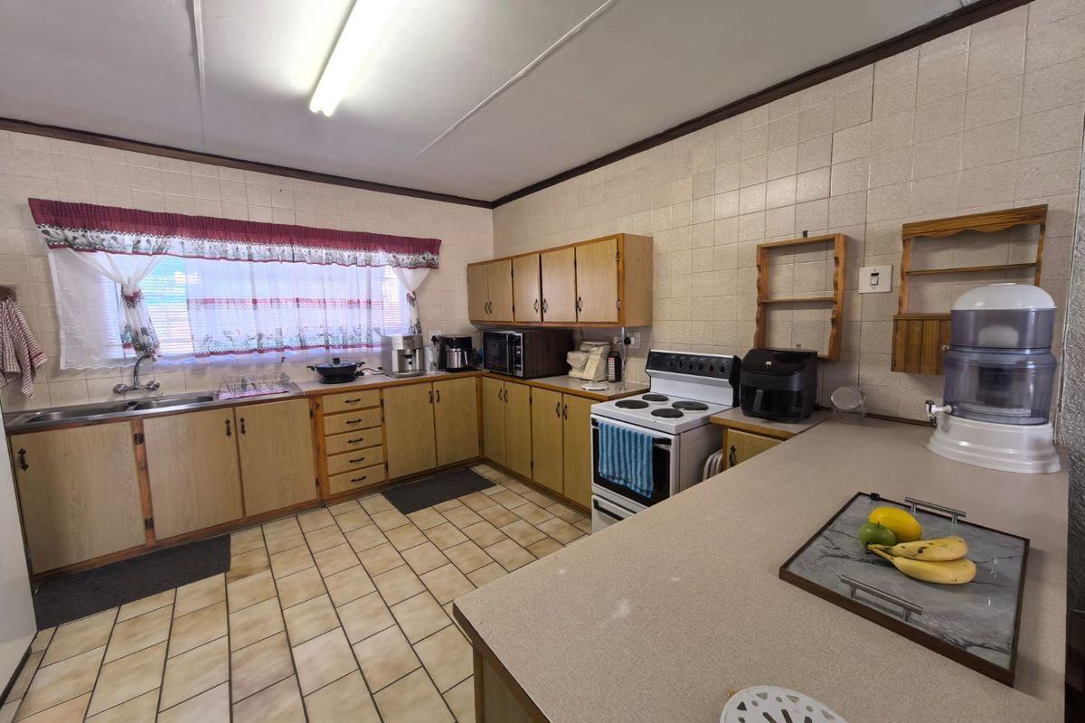 A functional kitchen featuring wood-finish cabinetry, tiled flooring, tiled splashbacks, and a freestanding stove, offering a practical layout for daily meal preparation.