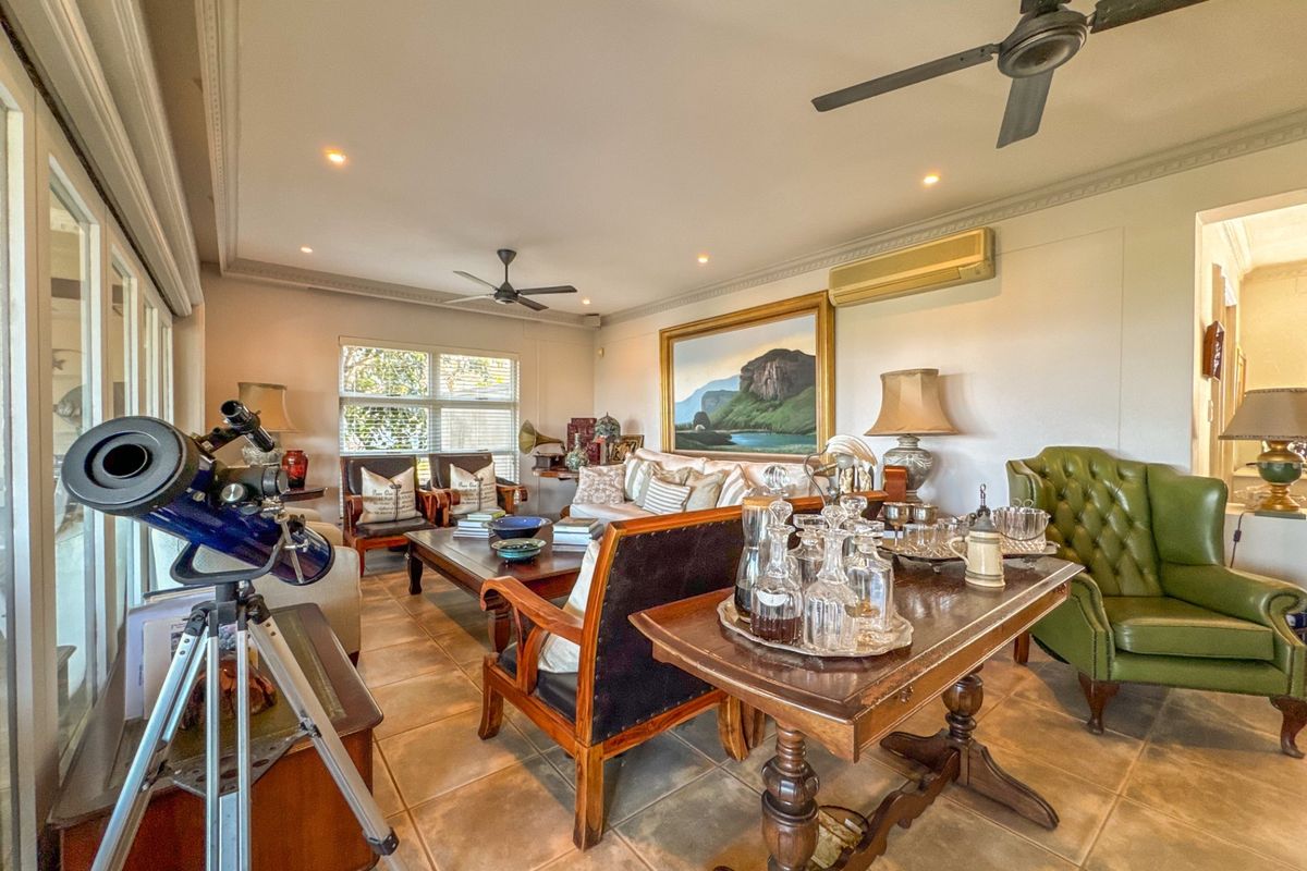 Spacious living room featuring tiled flooring, recessed downlighting, ceiling fans, and a wall-mounted air conditioning unit.