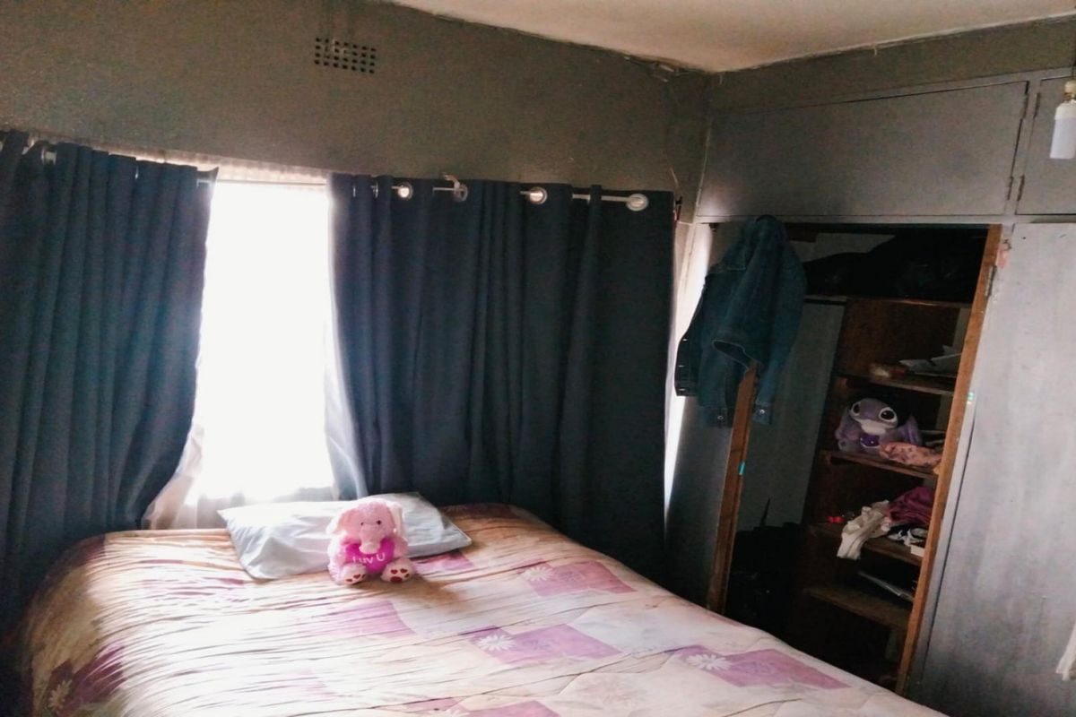 A bedroom featuring built-in storage cabinetry and a window with curtain fixtures.