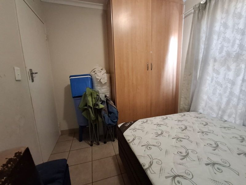A bedroom featuring tiled flooring and a built-in wooden wardrobe, offering a functional space with potential for cosmetic updates.
