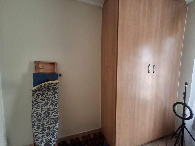 A bedroom interior featuring a large built-in wooden wardrobe with double doors.
